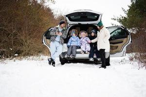 familie met kinderen zitten Aan auto suv met Open romp staan in winter Woud. foto