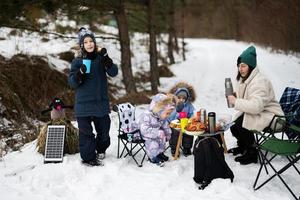 jong vrouw met kinderen in winter Woud Aan een picknick. moeder en drie kinderen. foto