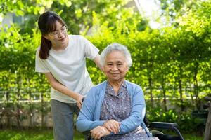 verzorger helpen en zorg Aziatisch ouderen vrouw gebruik wandelaar met sterk Gezondheid terwijl wandelen Bij park in gelukkig vers vakantie. foto