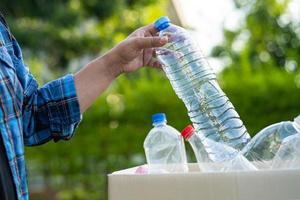 vrouw Holding plastic flessen vuilnis in doos naar hergebruik recycle voor mooi zo omgeving. foto