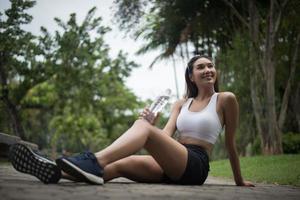 jonge sportieve vrouw zit in het park na een joggen foto