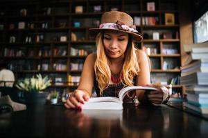 jonge vrouw die een boek leest in een café foto