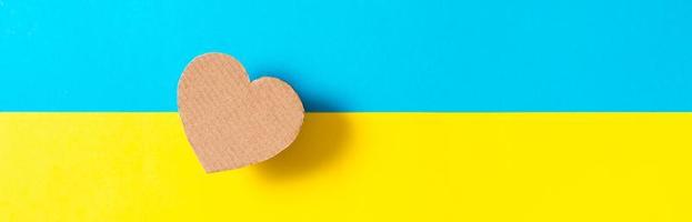de concept is Nee oorlog in Oekraïne. karton hart Aan de achtergrond van de oekraïens vlag. top visie. web banier foto