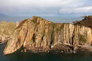 stilte strand, zilver-zanderig inham gesteund door een natuurlijk rots amfitheater in Asturië, Spanje. foto