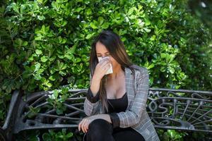 vrouw met stuifmeel allergie blazen neus- in de buurt struik foto