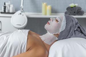 kant visie van een ontspannende vrouw in de spa salon gedurende de huid zorg behandeling met gazen in haar gezicht foto