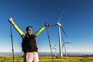 opgewonden ontdekkingsreiziger vieren succes in veld- met windmolens foto