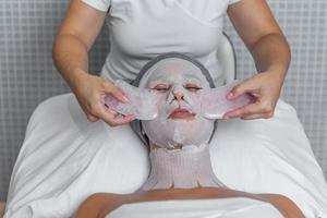 dichtbij omhoog van vrouw in spa ontvangen gua sha gelaats massage behandeling door schoonheidsspecialist foto