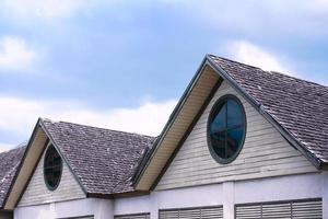 mooi houten huis dak met een ronde venster Aan blauw lucht achtergrond foto