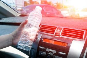 vrouw hand- Holding een plastic fles van water in de auto foto