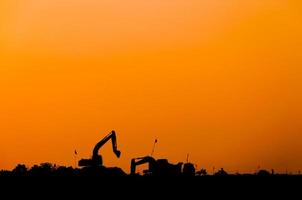 silhouet van graafmachine lader Bij bouw plaats, silhouet graaflaadmachine, rupstype lader graafmachine machine aan het doen grondverzet foto