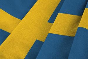 Zweden vlag met groot vouwen golvend dichtbij omhoog onder de studio licht binnenshuis. de officieel symbolen en kleuren in banier foto