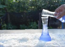wetenschapper is gieten een blauw oplossing van een wetenschap fles in een buis test in de modern laboratorium kamer. de onderwijs chemie en medisch wetenschap Onderzoek concept. foto