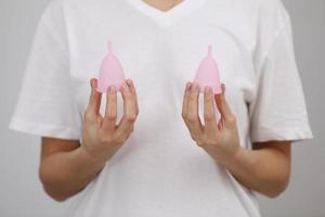 roze menstruatie- kopjes. dichtbij omhoog van vrouw hand- Holding verschillend grootte menstruatie- kopjes. Dames Gezondheid concept, nul verspilling alternatieven foto
