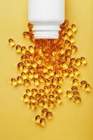 gouden omega-3 vis olie capsules gegoten uit van een pot Aan een geel achtergrond foto