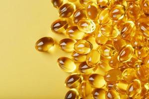 stapel van gouden capsules van vitamine d3 Aan een geel achtergrond met vrij ruimte foto