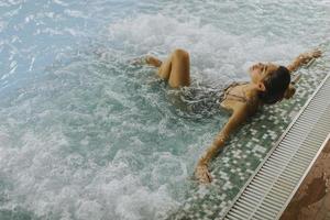 jonge vrouw ontspannen in het bubbelbad aan het zwembad foto