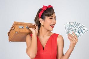 retro modieuze vrouw houdt bagage en geld om te reizen