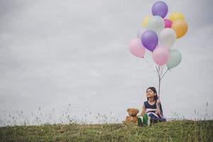 klein meisje spelen met ballonnen op weide veld foto