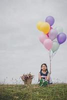 klein meisje spelen met ballonnen op weide veld foto