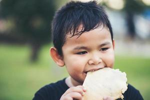 kleine jongen die een vers broodje sandwich eet foto