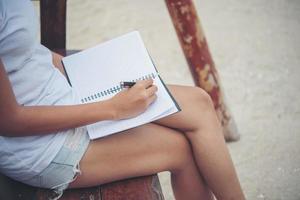 mooie jonge vrouw op een schommel die op haar blocnote schrijft