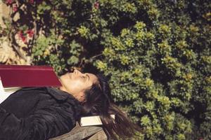 vrouw aan het liegen en slapen Aan een houten tafel met een boek foto