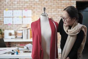 Aziatisch volwassen vrouw kostuum ontwerper meten vorm grootte van dressing marionet in een studio en werken met kleding, mode ontwerp verzameling, professioneel winkel kleermaker, naaister mkb ondernemer. foto