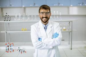 jonge wetenschapper in witte laboratoriumjas staande in het biomedische laboratorium foto