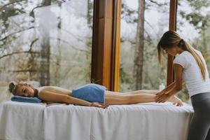 mooie jonge vrouw liggen en met beenmassage in spa salon tijdens winterseizoen foto