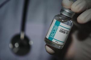 een mannelijke arts die een fles covid-19 of het coronavirusvaccin vasthoudt foto