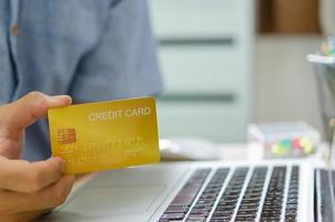 de hand van een man die een creditcard vasthoudt voor online transacties of online winkelen foto