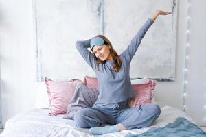 gelukkig gezond, mooi jong vrouw vervelend slaap masker en blauw pyjama, wakker foto