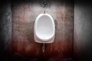 urinoir Aan oud beton rood muur, eng toilet foto