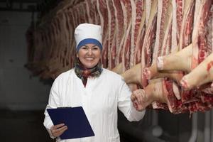 vleesverpakking fabriek arbeider in voorkant van afgeslacht karkassen. vlees productie. foto