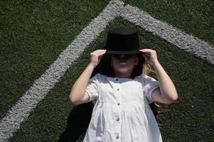 een meisje in een hoed, aan het liegen in de stadion. actief recreatie in een wit jurk foto