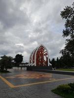 mataram, Indonesië, februari 16, 2023. een poort met de vorm van een wit traditioneel huis dak en een rood kleding motief in zongkareang park in de centrum van mataram stad foto