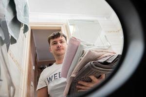 Mens visie van het wassen machine binnen. mannetje doet wasserij dagelijks routine. foto