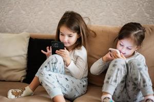 twee zussen slijtage pyjama spelen telefoons vroeg in ochtend. foto