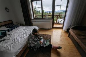 vrouw met laptop zittend Aan de verdieping en werken Aan laptop foto