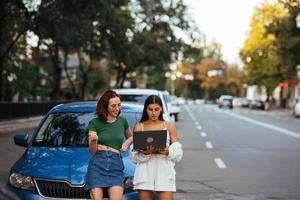 twee jong Dames met een laptop in de buurt de auto foto