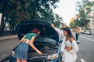 twee Dames met gebroken auto Aan de weg. Open kap foto