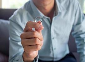 de man houdt de bruiloft ring na beslissen naar breken omhoog met zijn vrouw. foto