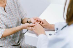 close-up arts houdt de hand van senior patiënt vast, verantwoordelijkheid voor medische zorg foto
