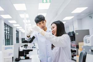 twee jonge medische wetenschappers kijken naar reageerbuis in medisch laboratorium, selecteer focus op mannelijke wetenschapper foto