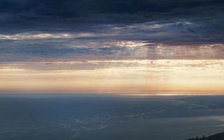 onweerswolken over- de zee Bij zonsondergang verdwijnen in de horizon foto