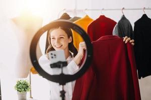 mooi dame blogger tonen kleren in voorkant van de camera naar opname vlog video leven streaming Bij haar winkel. online boodschappen doen kar begrip. foto