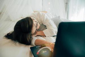 freelance en afgelegen werk. chronisch vermoeidheid syndroom en laag macht accu, bedrijf vrouw slapen over- een laptop. jong moe vrouw vallen in slaap. overwerkt, niveau indicator van laag energie resterend 15 foto