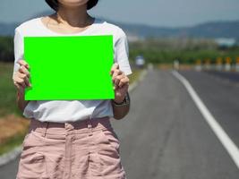 vrouw Holding een groen kopiëren papier. Aan de straat. ruimte voor advertentie. foto