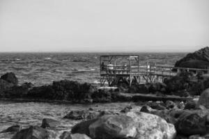 ontspannende Aan houten platform Aan de zee in zwart en wit foto